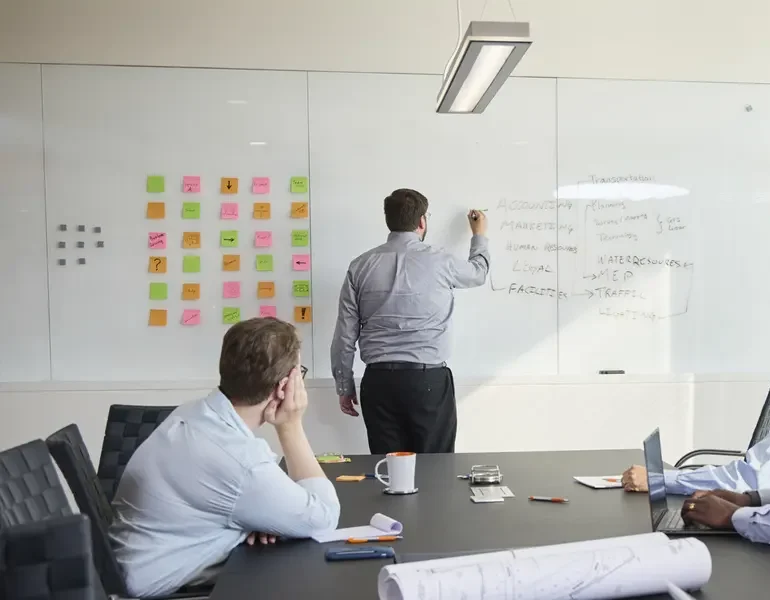 Team sitting at a table looking at the white board