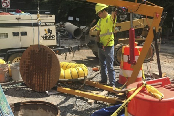 Worker raising a manhole cover