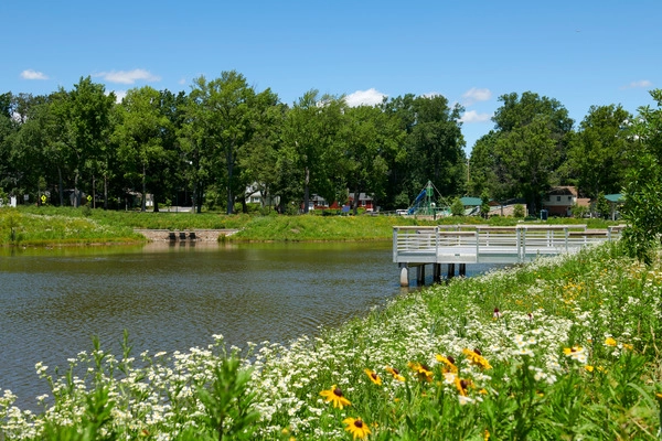 Pond with fishing deck and grassy area with flowers